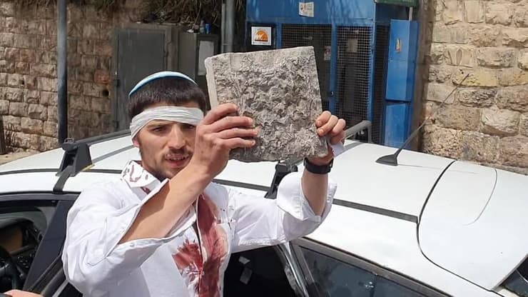 שחור מציג את אחת האבנים שהושלכו לעבר רכבו במטרה לפגוע בו ובחבריו תיעוד אבן