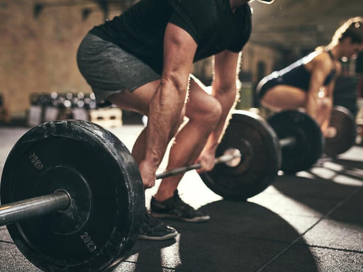 אימוני כוח קריטיים לשימור מסת השריר במהלך טיפול בזריקות הרזיה (shutterstock) גבר מבצע דדליפט בחדר כושר