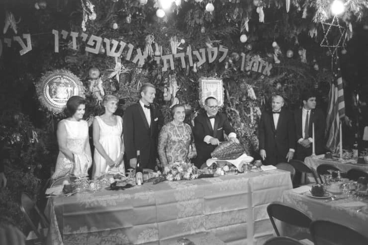 רה"מ גולדה מאיר מתארחת בסוכה בברוקלין בשנת 1969 (צילום: משה מילנר, לע"מ) בלט בהיעדרו: יצחק רבין. רה"מ גולדה מאיר ושאר המכובדים בסוכה בברוקלין