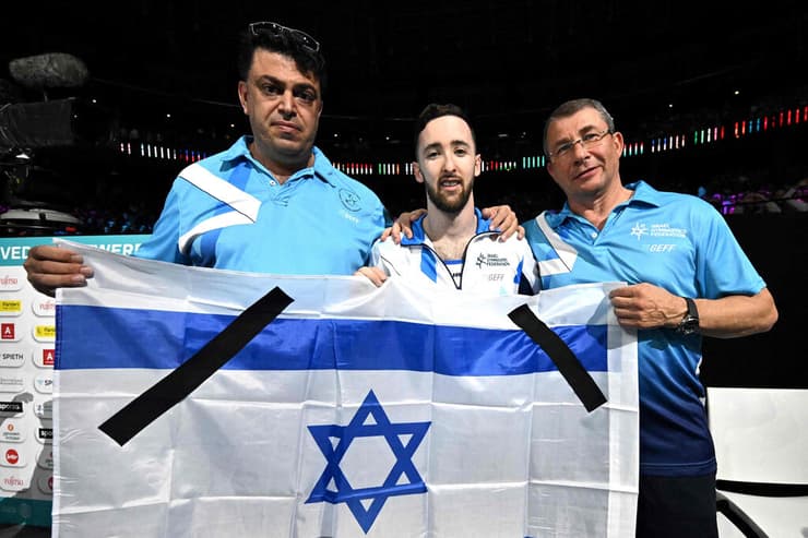 דולגופיאט ומאמניו עם דגל ישראל והסרטים השחורים אחרי הזכייה ההיא ב-7 באוקטובר 2023 (צילום: Lionel BONAVENTURE / AFP) דולגופיאט