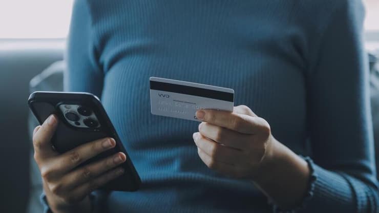 הסמארטפון כבר מזמן הפך למוצר צריכה בסיסי (צילום: shutterstock) אישה עם טלפון וכרטיס אשראי