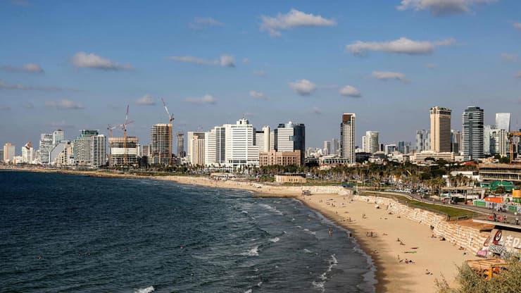 אנשים משתזפים ומשתכשכים במימי הים התיכון לאורך חוף הים בתל אביב