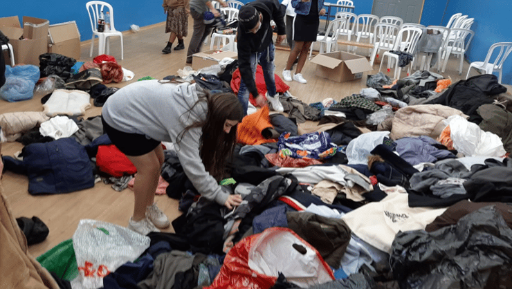 קיפול, סידור ומכירת ביגוד על מנת לסייע לנזקקים (צילום: באדיבות עמותת "רוח טובה" מקבוצת אריסון) אוספים מעילים מהשכונה