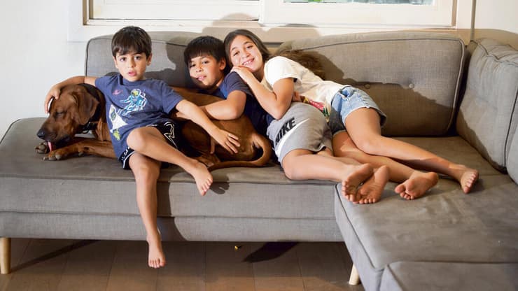 "הילדים היו מתחת לזרקורים מהרגע שהם חזרו, והם יודעים שזה נמשך כי החטופים עדיין שם". עפרי, יובל ואוריה ברודץ' עם הכלב רודני (צילום: זיו קורן) yk14162173