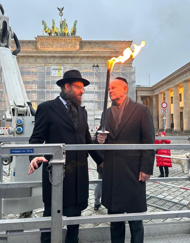 הרב טייכטל מדליק נר חנוכה בשנה שעברה עם הקנצלר הגרמני ב"שער הניצחון" בלב ברלין
