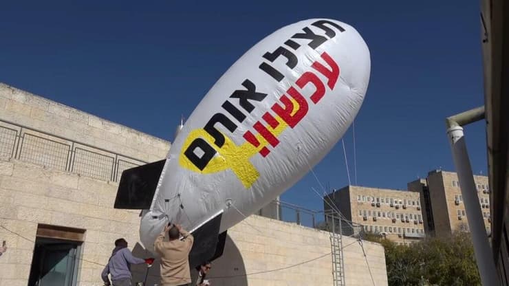 צפלין מעל הגג של מוזיאון המדע בירושלים מול לשכת רה"מ במחאה למען השבת החטופים ועליו הכיתוב: "החזירו אותם הביתה עכשיו"