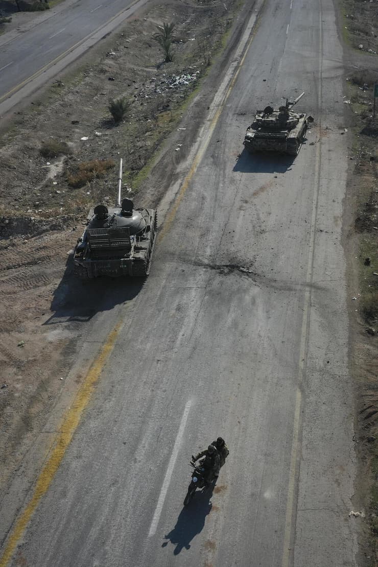 מורדים סורים רוכבים על אופנועים בין כלי רכב נטושים של הצבא הסורי ב כביש ב פאתי חמה סוריה
