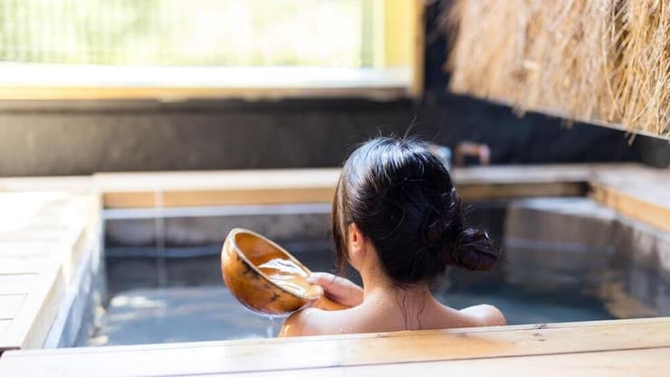 אישה אסייתית צעירה נרגעת באונסן