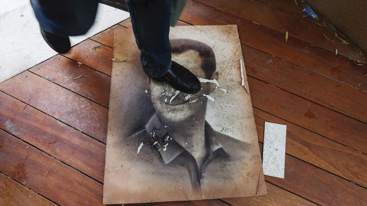 אדם דורך על תמונתו של בשאר אל-אסד עם כניסת המורדים לארמון בדמשק