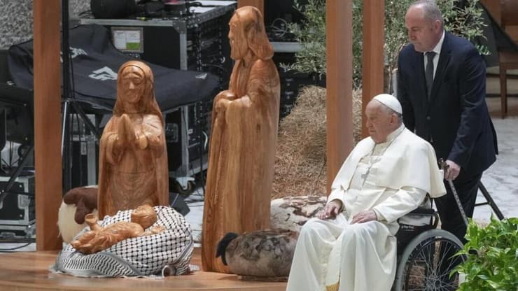 ותיקן אפיפיור פרנסיסקוס תפילה מול בובת ישו ב אבוס עם כאפייה פלסטינית