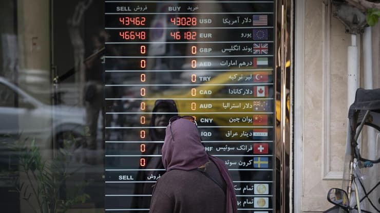 אישה איראנית מול לוח אלקטרוני של המרת מטבע בטהרן (צילום: Morteza Nikoubazl, GettyImages) אישה איראנית מול לוח אלקטרוני של המרת מטבע בטהרן
