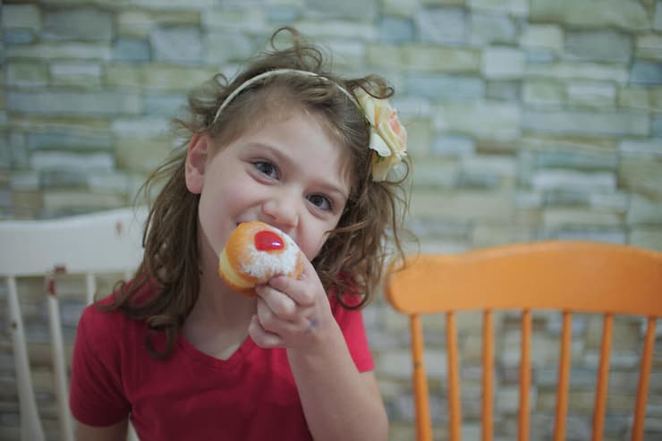 ילדה אוכלת סופגנייה חנוכה