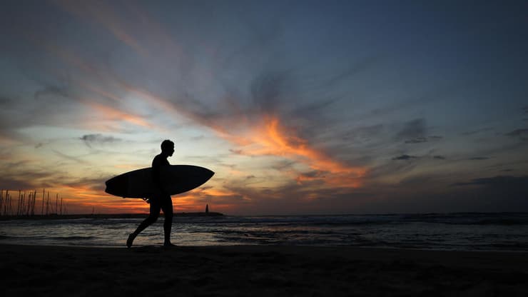 גולש בחוף הים בתל אביב (צילום: REUTERS/Kai Pfaffenbach) שקיעה בתל אביב