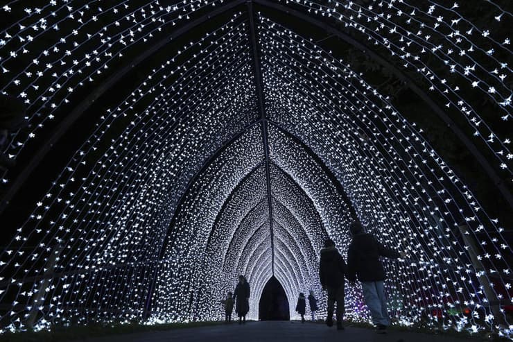 מבקרים צועדים דרך ה"קתדרלה" בשביל אורות חג המולד, שחוזר לשנתו ה-12, עם תצוגה של מיצבים חדשים בתוך נוף אתר המורשת העולמית של אונסק"ו בגני קיו בלונדון (AP Photo/Kirsty Wigglesworth) מבקרים צועדים דרך ה"קתדרלה" בשביל אורות חג המולד, שחוזר לשנתו ה-12, עם תצוגה של מיצבים חדשים בתוך נוף אתר המורשת העולמית של אונסק"ו בגני קיו בלונדון