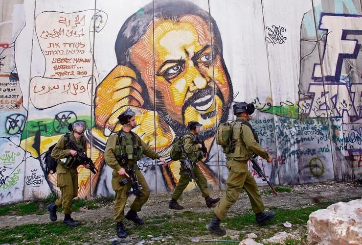 חיילים על רקע גרפיטי לשחרור מרוואן ברגותי במחסום קלנדיה, ליד רמאללה