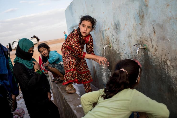 ילדה סורית ממלאת בקבוק מים במחנה הפליטים הסורי שבעין איסא