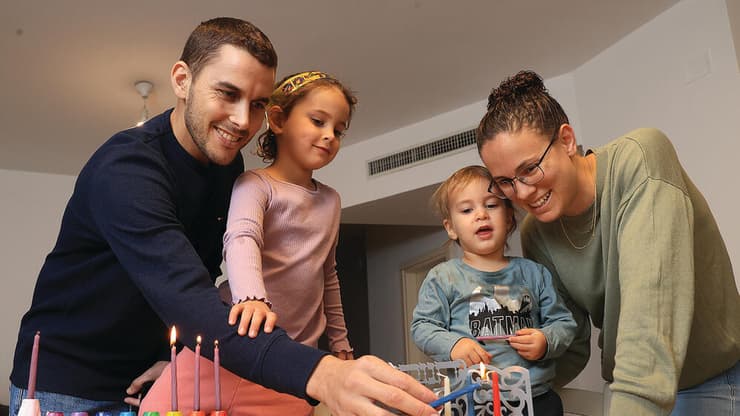 סא"ל יהודה שלו מדליק נרות חנוכה עם משפחתו, כחודשיים לאחר הפציעה (צילום: אלעד גרשגורן) yk14202720