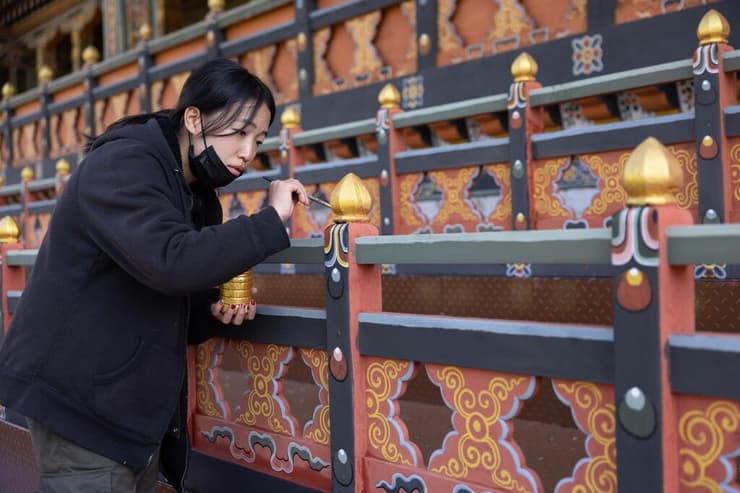 נערה בשעת מלאכת צביעת עבודות העץ במקדש מקומי (צילום: טל שחר) נערה בשעת מלאכת צביעת עבודות העץ במקדש מקומי