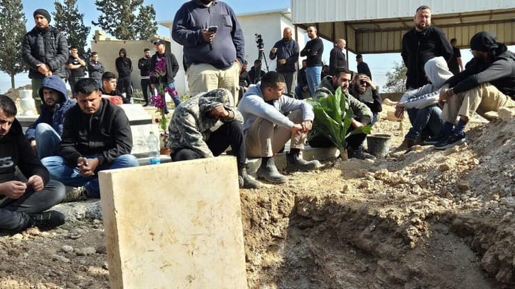 אבלים מחכים לצד בור הקבורה בו יקבר חמזה אל-זיאדנה