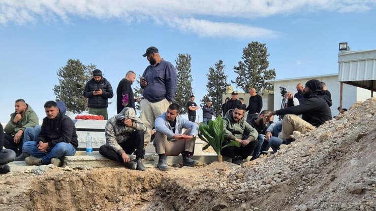 אבלים מחכים לצד בור הקבורה בו יקבר חמזה אל-זיאדנה