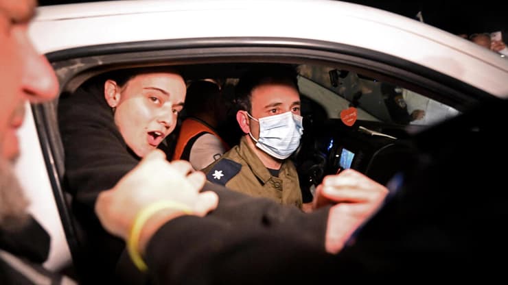  אמילי דמארי מוציאה את ראשה מהרכב שמוביל אותה לביה"ח שיבא ולוחצת ידיים לתומכים  