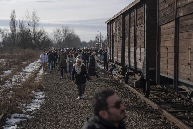 מבקרים ליד קרונות הרכבת באושוויץ