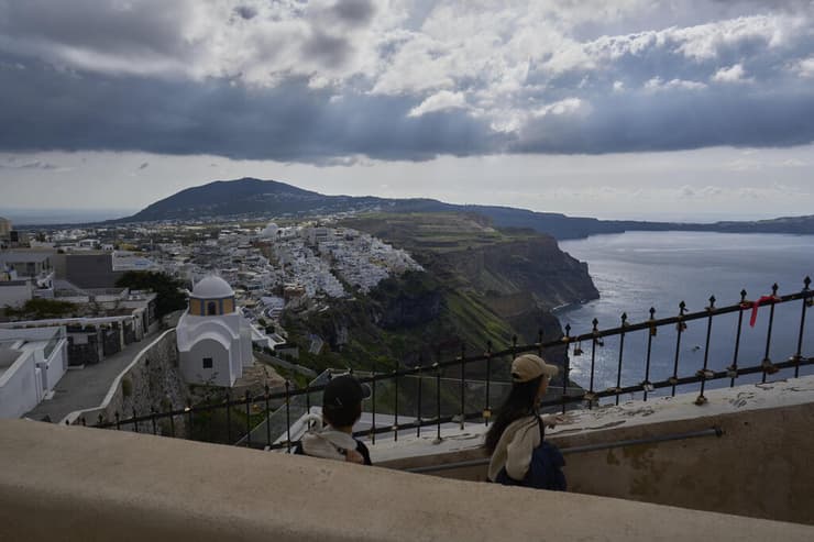 תיירים הולכים ברחובות הצרים של פירה שבסנטוריני, בזמן שצוותי חירום נפרסו בעקבות עלייה בפעילות הסיסמית (צילום: Petros Giannakouris, AP) תיירים הולכים ברחובות הצרים של פירה שבסנטוריני, בזמן שצוותי חירום נפרסו בעקבות עלייה בפעילות הסיסמית