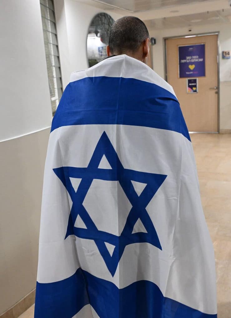 אליהו (אלי) שרעבי עטוף בדגל ישראל, עם הגעתו לבית החולים שיבא