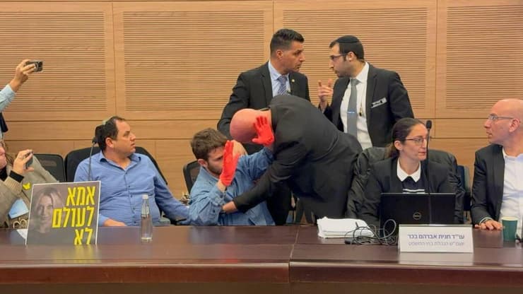 אדם שלא מזוהה עם אחד הארגונים ונכח בוועדת החוקה, הציג ״ידיים מגואלות בדם״