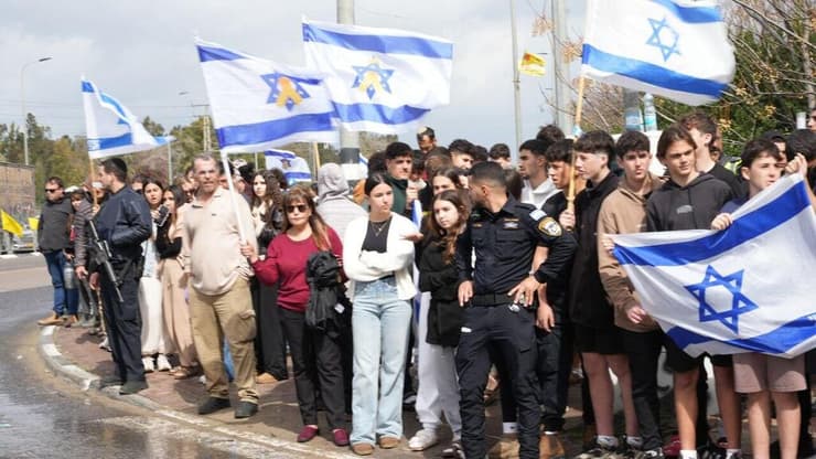 עם דגלי ישראל, לפני מעבר הרכבים שהובילו את ארונות החטופים החללים. עשרות בצומת יד מרדכי (צילום: תומר שונם הלוי) אזרחים תומכים ושוטרים מצדיעים בצומת יד מרדכי במהלך קבלת החטופים החללים והעברתן לאבו כביר