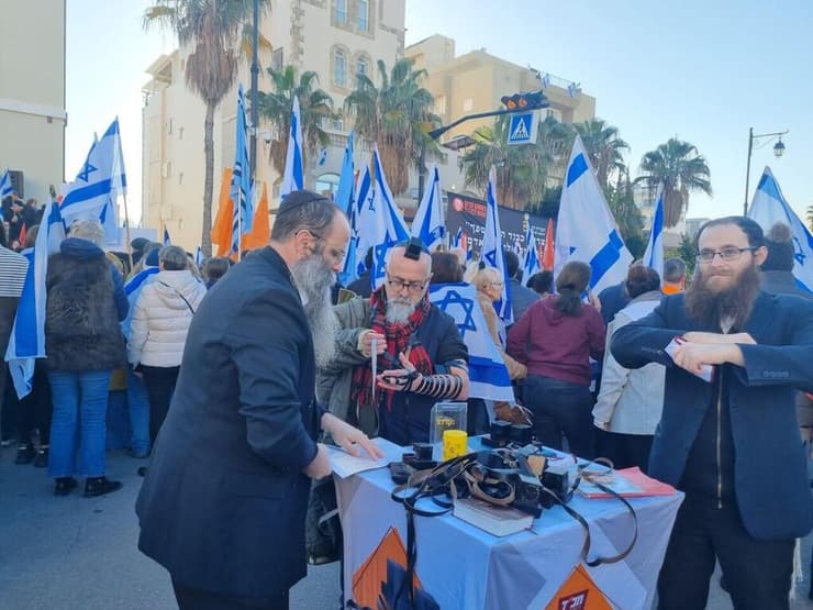מניחים תפילין בזמן מסע ההלוויה