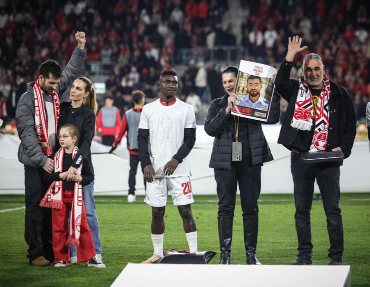 שורד השבי שגיא דקל-חן עם בתו ואשתו לצד משפחתו של רן גואילי ז"ל לפני המשחק בין הפועל באר-שבע למכבי חיפה