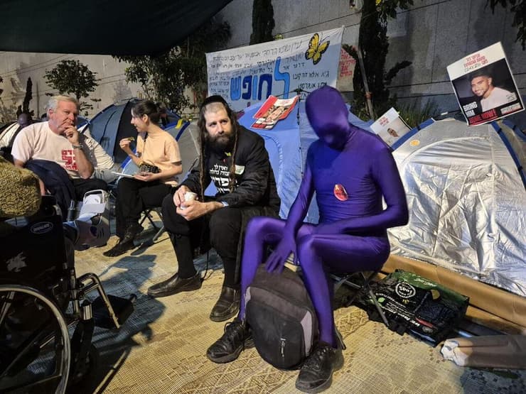 שהסיפור יהפוך למציאות. צבי דביר וחבר (צילום: יואב קרן ) צבע במאהל בשער בגין: בחור חרדי לבוש שחורים ומגודל פאות משוחח עם גבר עטוי בגד גוף סגול