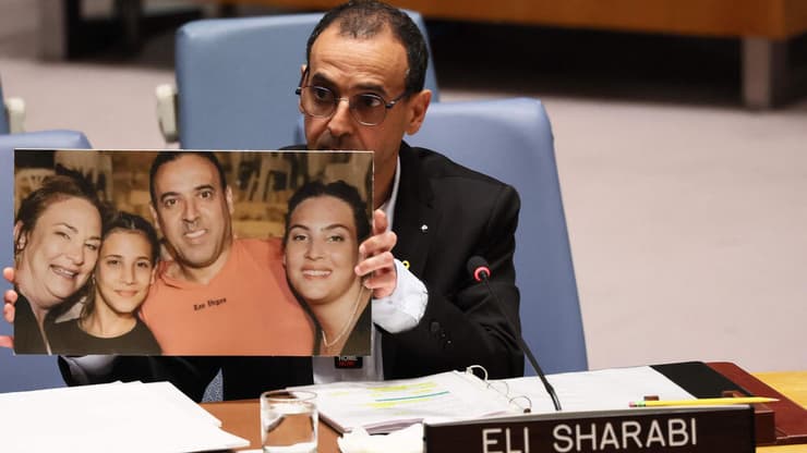 מציג את תמונת בני משפחתו, שנרצחו בטבח. "קרעו אותי מהמשפחה שלי, מאז לא ראיתי אותם שוב" (צילום: Michael M. Santiago / GETTY IMAGES NORTH AMERICA / AFP) אלי שרעבי שורד השבי נואם באו"ם
