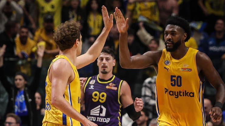 שחקן מכבי ת"א טרביון וויליאמס עם רוקאס יוקובאיטיס מול שחקן הפועל חולון יפתח זיו