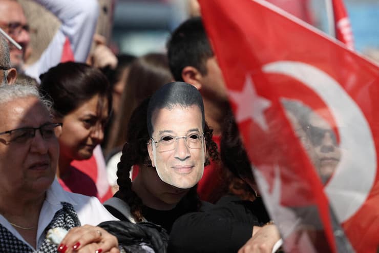 אחד המפגינים עם מסכה בדמותו של אימאמאולו (צילום: REUTERS/Umit Bektas' REUTERS/Louisa Gouliamaki) עצרת הפגנה ענקית ב איסטנבול טורקיה נגד מעצר יריבו המרכזי של ארדואן , אכרם אימאמאולו