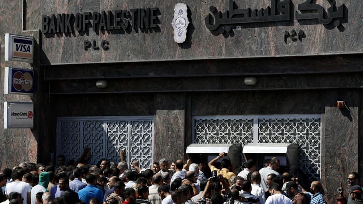 פלסטינים מתגודדים בתור לכספומט בבנק פלסטין (צילום: AP Photo/Lefteris Pitarakis) פלסטינים מתגודדים בתור לכספומט בבנק פלסטין