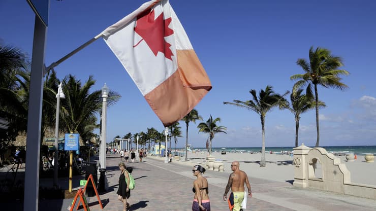 דגל קנדה מתנוסס בחוף הים בפלורידה. קנדים מהווים כ-13% מרוכשי הנכסים הזרים בארה"ב