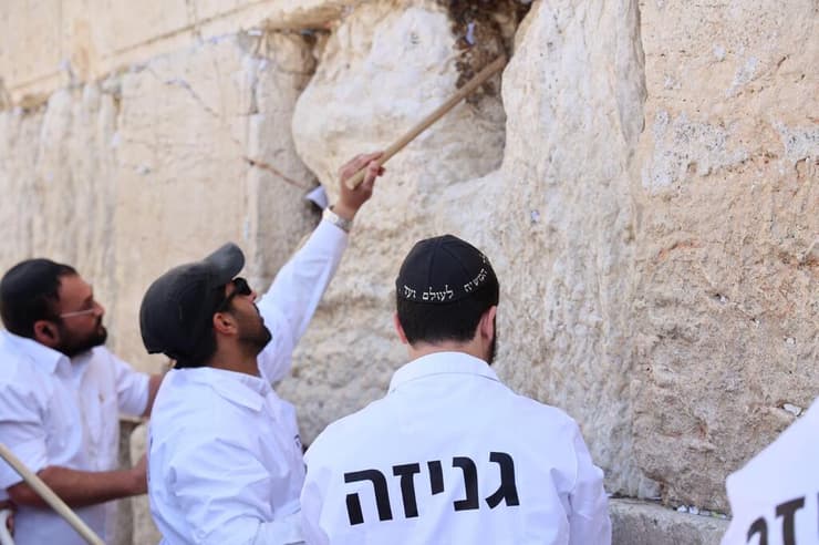 מוציאים פתקים מהכותל באמצעות מקלות עץ (צילום: הקרן למורשת הכותל המערבי) מוציאים פתקים מהכותל המערבי באמצעות מקלות עץ