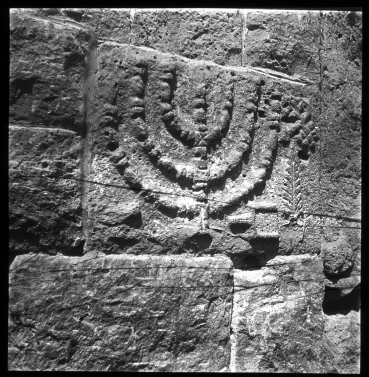 מנורה בתבליט עתיק על קיר בית כנסת בדרום סוריה. היסטוריה יהודית עשירה