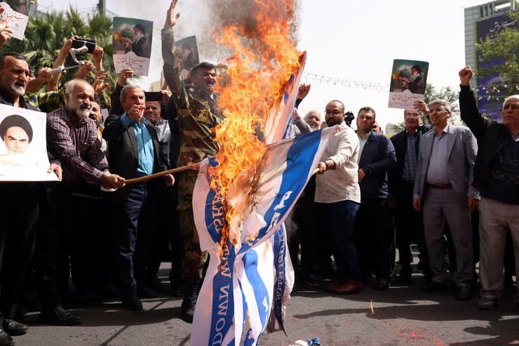 תומכי המשטר האיראני שורפים את דגל ישראל, אתמול בכיכר פלסטין בטהרן (צילום: ATTA KENARE / AFP) איראן טהרן כיכר פלסטין שורפים דגלים הפגנה למען עזה