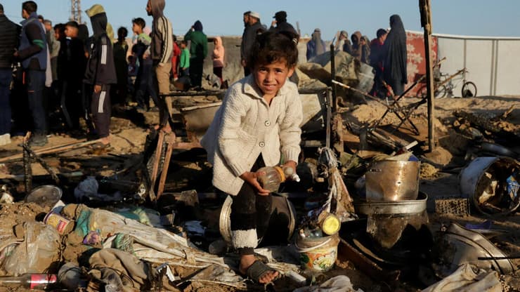 צילום:REUTERS/Hatem Khaled ילד עזתי מסתכל על נזק באתר בו תקפה ישראל בחאן יונס