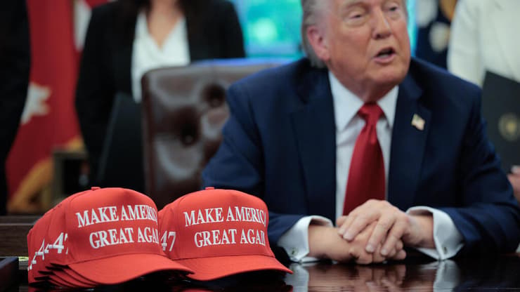 טראמפ לצד כובעי MAGA. "רבים מונעים ממטרות מסחריות, ומשתמשים בפוליטיקה כאמצעי" (צילום: Chip Somodevilla/Getty Images) נשיא ארה"ב טראמפ בחדר הסגלגל עם כובע MAGA