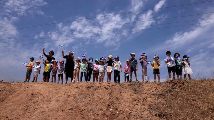 ילדי קיבוץ עלומים מנופפים בגדלי ישראל