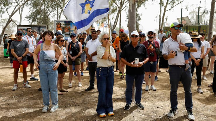 הצפירה במתחם הנובה (צילום: REUTERS/Amir Cohen) אזרחים עומדים במהלך צפירת יום הזיכרון לחללי מערכות ישראל ונפגעי פעולות איבה