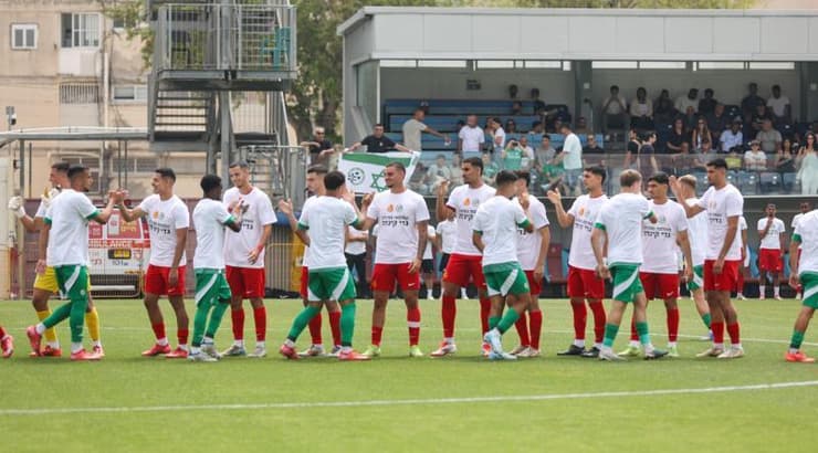 שחקני הקבוצות לוחצים ידיים עם חולצות המחווה לגדי קינדה