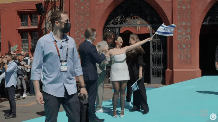 יובל רפאל על הבמה ולצידה המאבטח (צילום מסך) יובל רפאל במצעד המשלחות