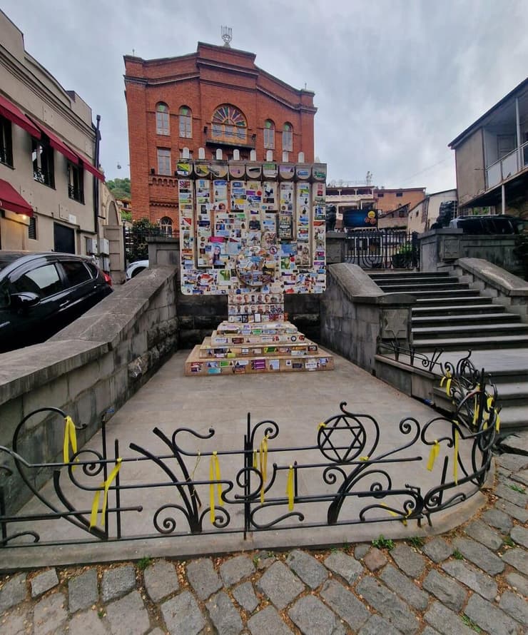 סטיקרים לזכר הנופלים וסרטים צהובים בקריאה להשבת החטופים מחוץ לבית הכנסת הגדול בטביליסי