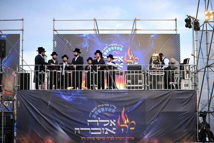 טקס "אֵלֶּה אַזְכֵּרָה" לזכר 45 הנספים באסון מירון (צילום: יוסי בן שושן, דוברות הילולת רשב"י) טקס “אֵלֶּה אַזְכֵּרָה” לזכר 45 קדושי מירון, במתחם ההילולא המורחב במירון – המעמד נפתח באמירת פרקי תהילים לרפואת הפצועים ולהשבת החטופים, בשילוב שירת "אחינו כל בית ישראל"
