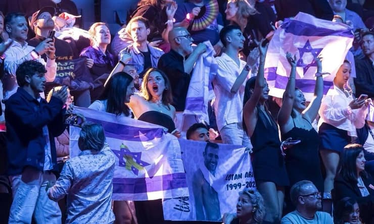 הילה אביר מניפה את הדגל בקהל, בזמן הופעת חצי הגמר של יובל רפאל